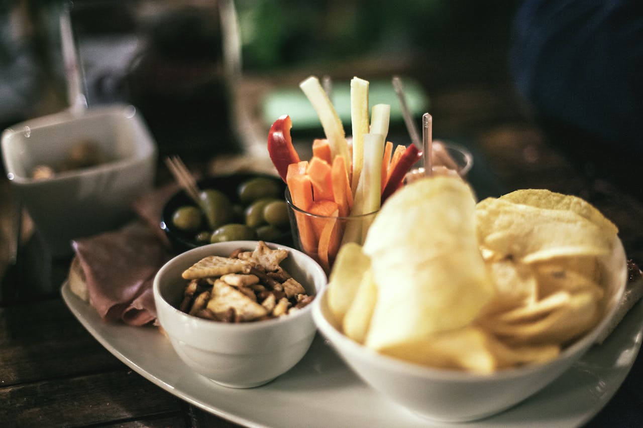 services-05 A tempting snack platter featuring crisps, vegetables, and olives, perfect for a casual gathering.